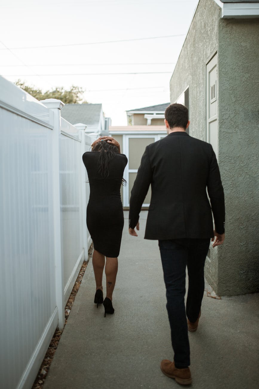man and woman walking beside the fence